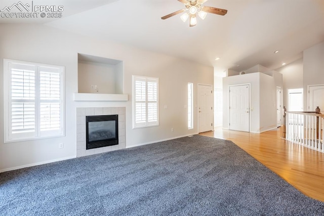 unfurnished living room featuring lofted ceiling, wood-type flooring, a tile fireplace, and ceiling fan