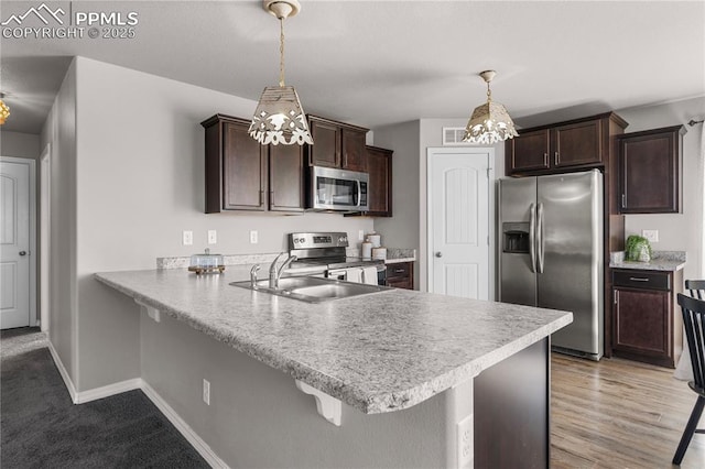 kitchen with pendant lighting, stainless steel appliances, a kitchen breakfast bar, and kitchen peninsula