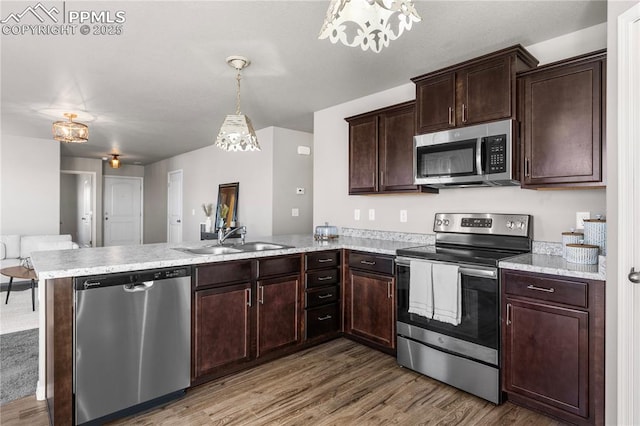 kitchen with sink, hardwood / wood-style floors, hanging light fixtures, stainless steel appliances, and kitchen peninsula