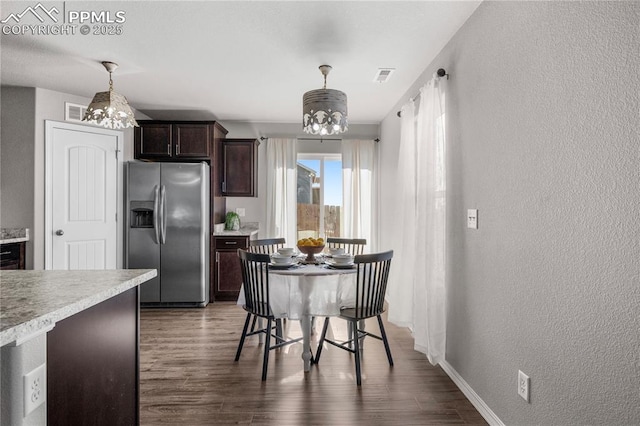 kitchen featuring dark wood-type flooring, a chandelier, dark brown cabinets, stainless steel fridge, and pendant lighting