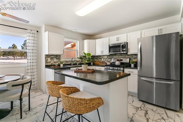 kitchen with appliances with stainless steel finishes, a breakfast bar, a kitchen island, and white cabinets