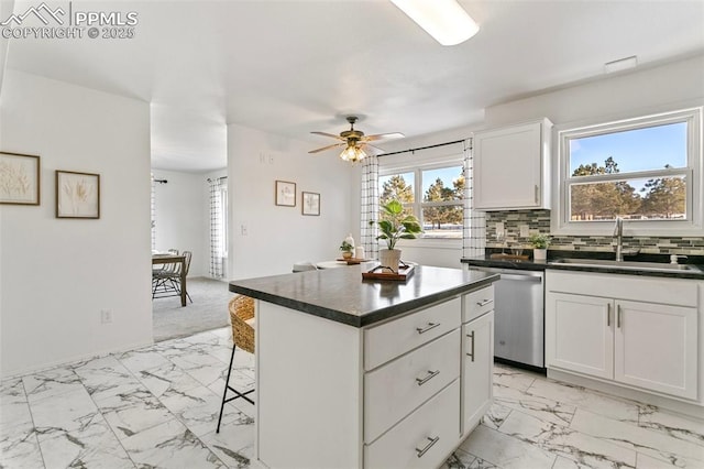 kitchen featuring a kitchen island, dishwasher, sink, white cabinets, and a kitchen bar