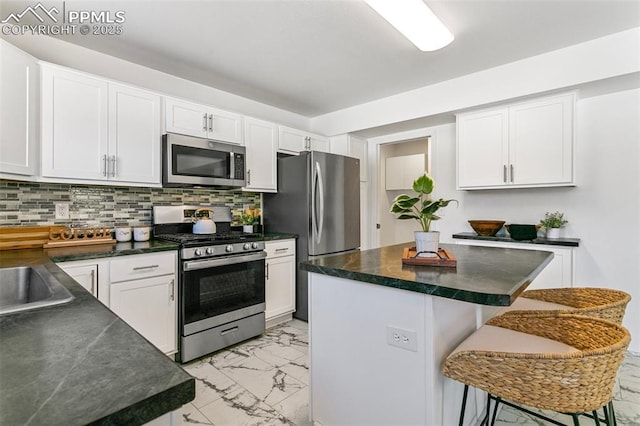 kitchen featuring white cabinetry, a kitchen island, stainless steel appliances, and a kitchen bar