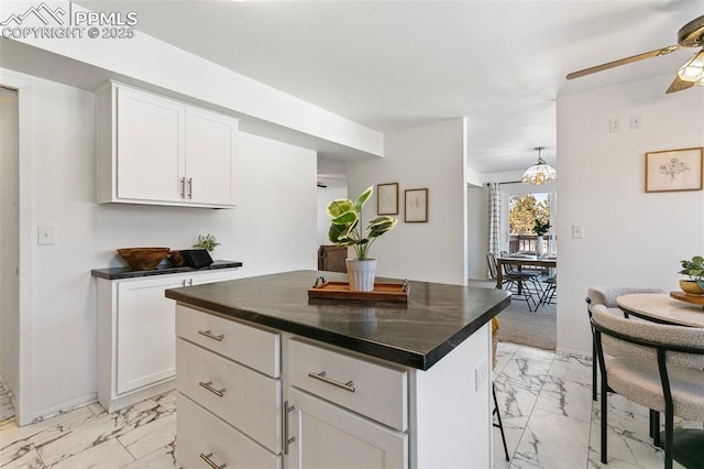 kitchen with white cabinetry, a kitchen breakfast bar, ceiling fan, and a kitchen island