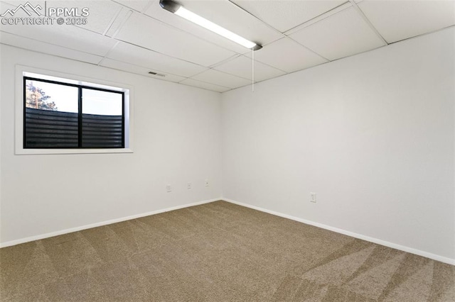 carpeted empty room featuring a drop ceiling