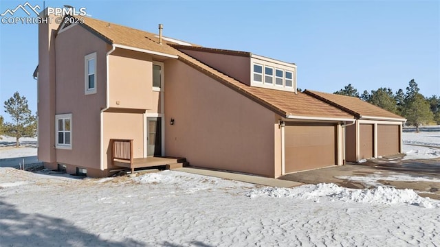 snow covered house featuring a garage