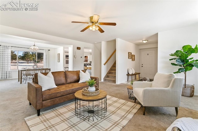 living room featuring light colored carpet and ceiling fan with notable chandelier