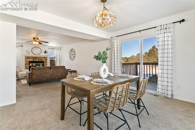 dining area with ceiling fan, carpet floors, and a fireplace