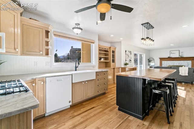 kitchen with a center island, light brown cabinetry, dishwasher, and hanging light fixtures