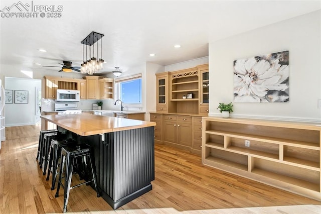 kitchen with decorative light fixtures, a breakfast bar, light hardwood / wood-style flooring, and light brown cabinetry