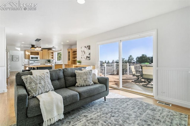 living room featuring ceiling fan, sink, and light hardwood / wood-style flooring