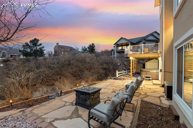 patio terrace at dusk featuring a fire pit and a hot tub