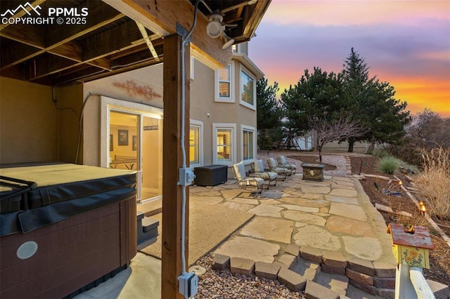 patio terrace at dusk featuring a hot tub