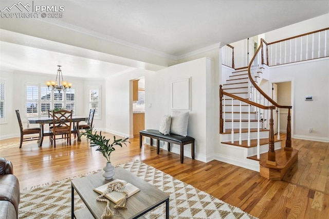 living room featuring a notable chandelier, ornamental molding, and light hardwood / wood-style floors