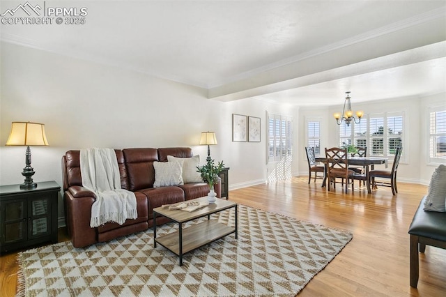 living room featuring ornamental molding, a chandelier, and light hardwood / wood-style flooring