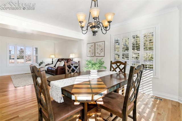 dining space with light hardwood / wood-style flooring, ornamental molding, and a chandelier