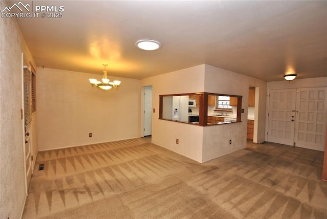 unfurnished living room with carpet floors and a chandelier