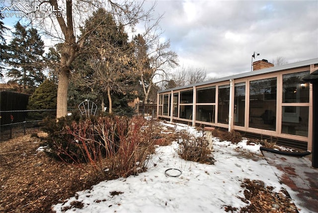 yard covered in snow with a sunroom