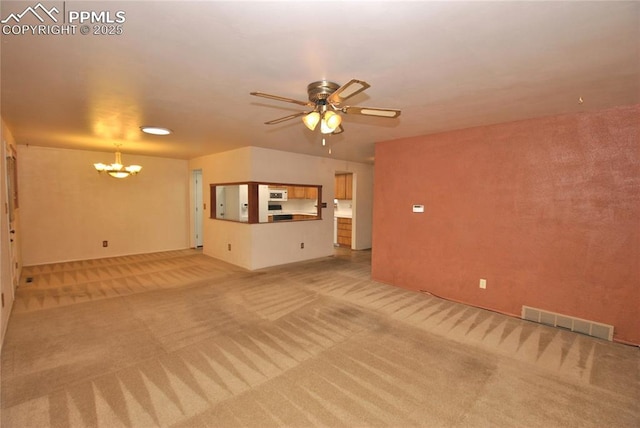 unfurnished living room with ceiling fan with notable chandelier and light colored carpet