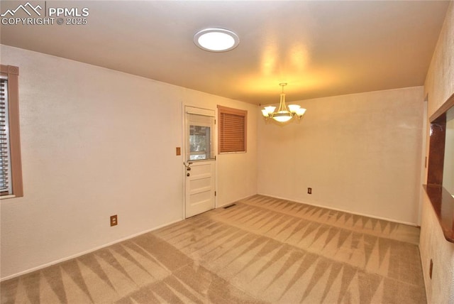 unfurnished room with carpet floors and an inviting chandelier