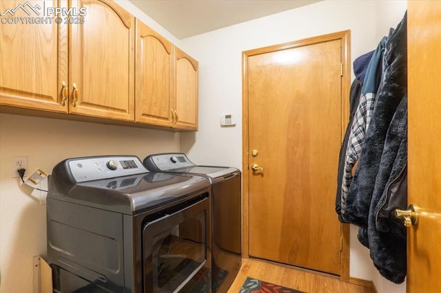 clothes washing area featuring cabinets, washer and clothes dryer, and light hardwood / wood-style flooring