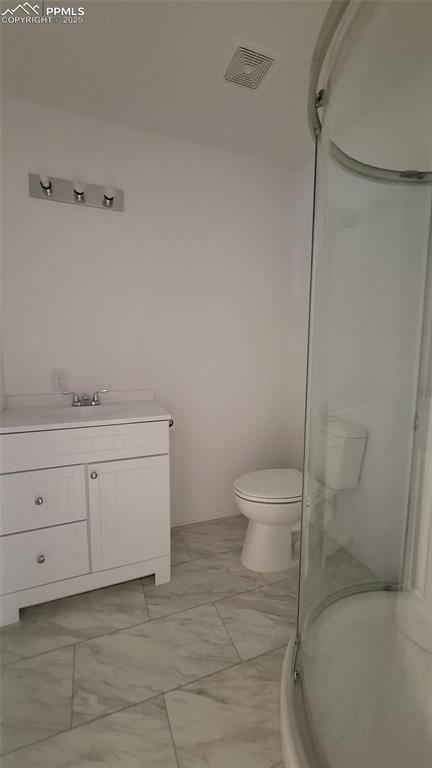 bathroom with vanity, a shower with shower door, and toilet