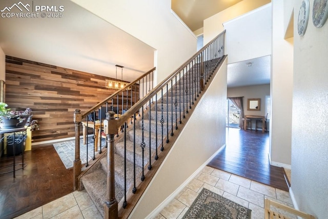 staircase featuring tile patterned flooring, an inviting chandelier, and wooden walls