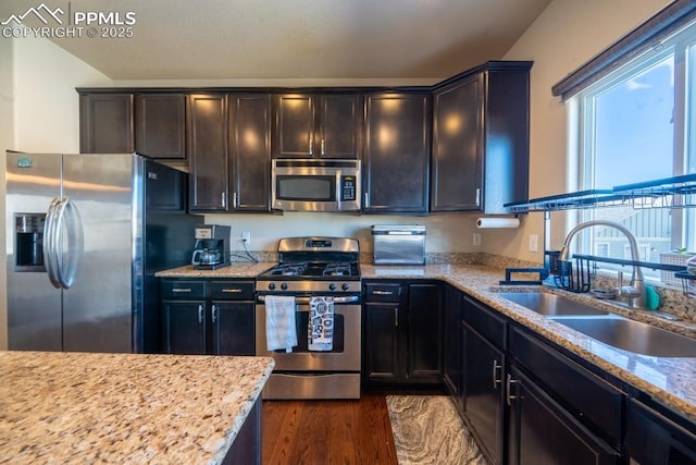 kitchen with dark wood-type flooring, stainless steel appliances, light stone countertops, and sink