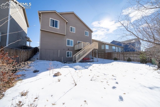 snow covered rear of property featuring a deck