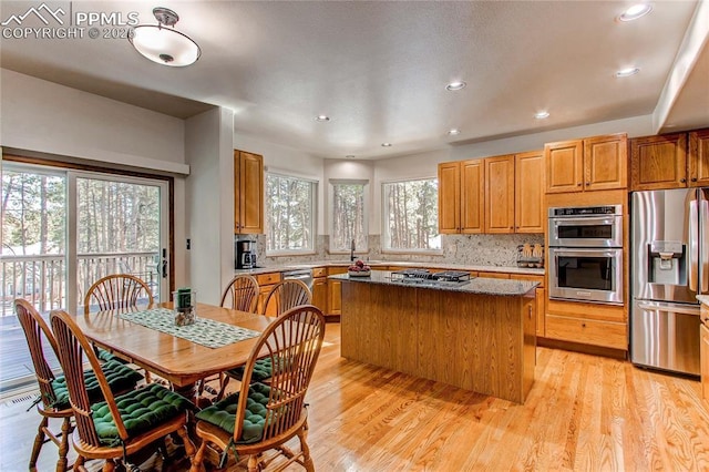 kitchen featuring stainless steel appliances, a center island, decorative backsplash, and light wood-type flooring