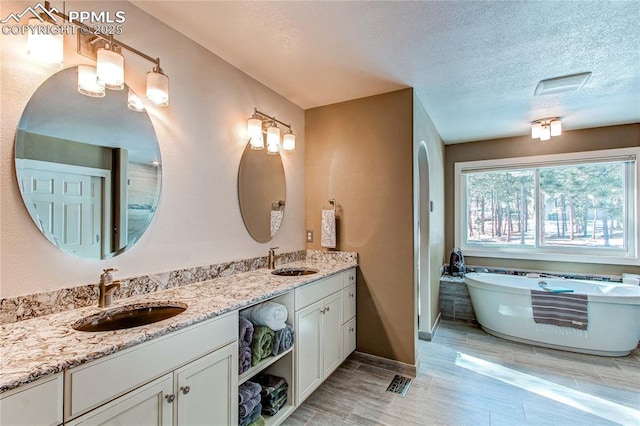 bathroom featuring vanity, a washtub, and a textured ceiling