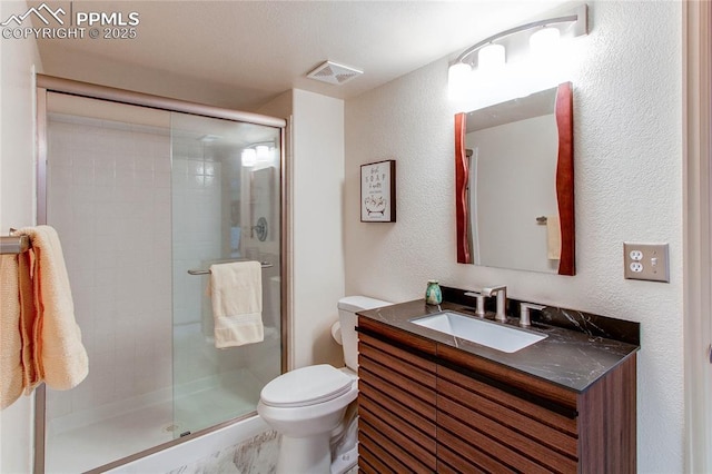 bathroom with a shower with door, vanity, and toilet