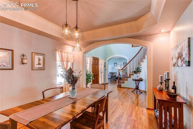 dining room with crown molding, a raised ceiling, and light hardwood / wood-style floors