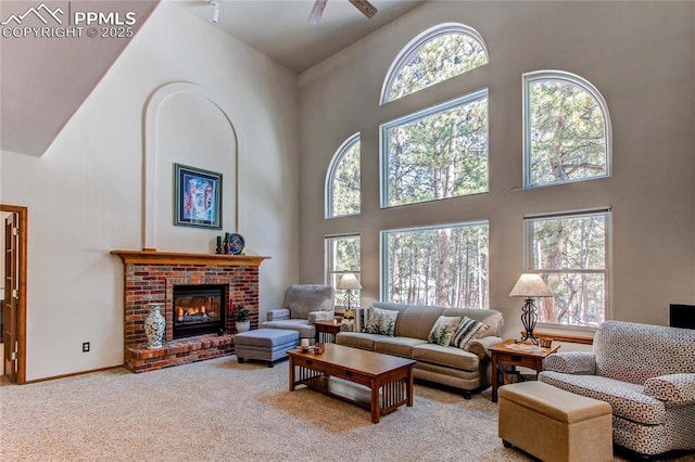 living room featuring a brick fireplace, a healthy amount of sunlight, carpet, and high vaulted ceiling