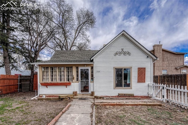 view of front facade with roof with shingles and a fenced backyard