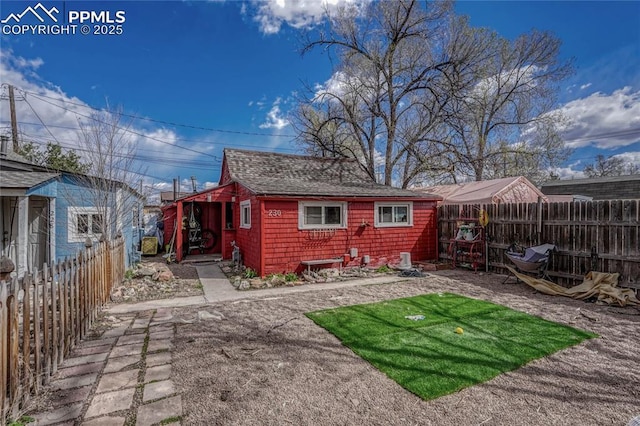 rear view of house featuring a patio, a fenced backyard, and a shingled roof