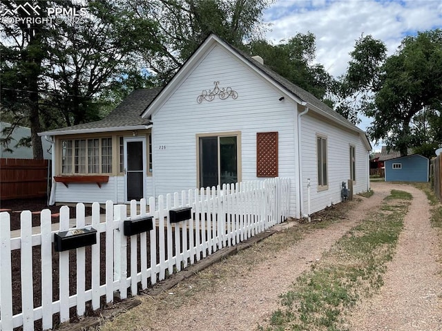 view of front of home with a sunroom, a fenced front yard, and roof with shingles