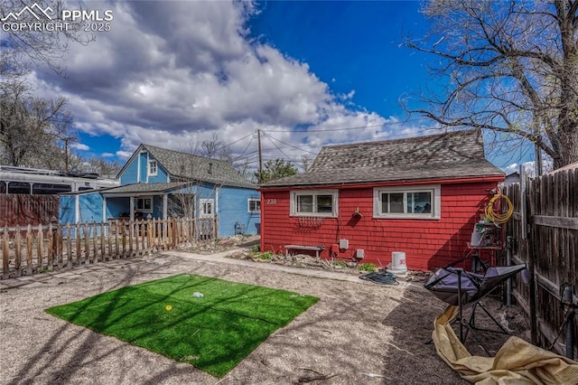 rear view of house with fence private yard and a shingled roof