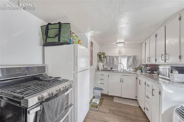 kitchen with a sink, stainless steel range with gas cooktop, light wood-style flooring, and white cabinets