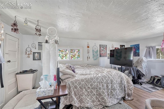 bedroom with a textured ceiling and wood finished floors