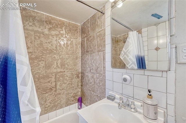 bathroom featuring a sink, decorative backsplash, shower / bath combo with shower curtain, and tile walls