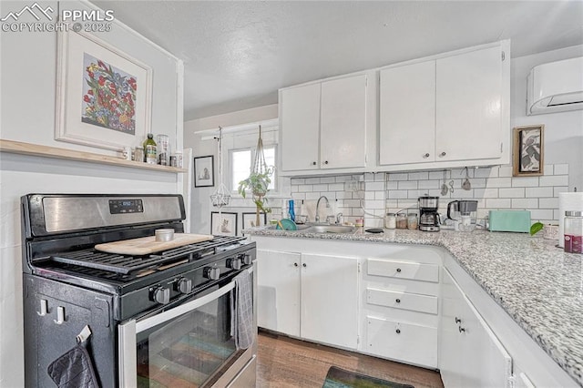 kitchen featuring a sink, decorative backsplash, gas range, and white cabinetry