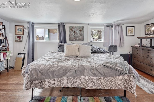 bedroom featuring multiple windows, a textured ceiling, and wood finished floors