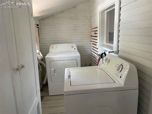 laundry area featuring wooden walls, independent washer and dryer, and laundry area