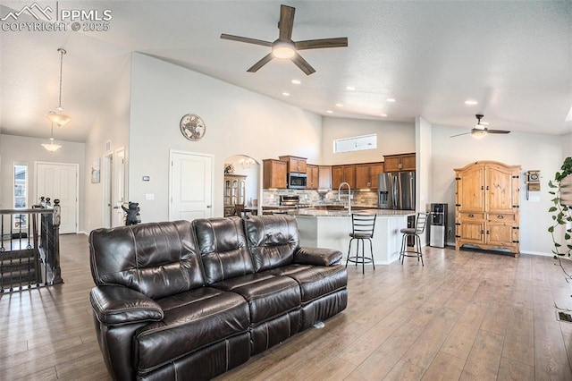 living room featuring wood-type flooring, ceiling fan, and high vaulted ceiling