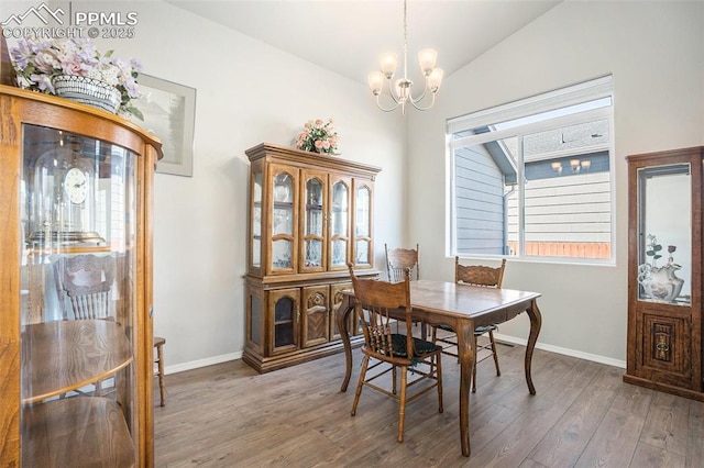 dining area with lofted ceiling, a notable chandelier, and dark hardwood / wood-style flooring