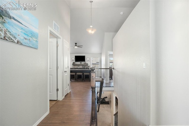 hallway with a towering ceiling and dark hardwood / wood-style floors