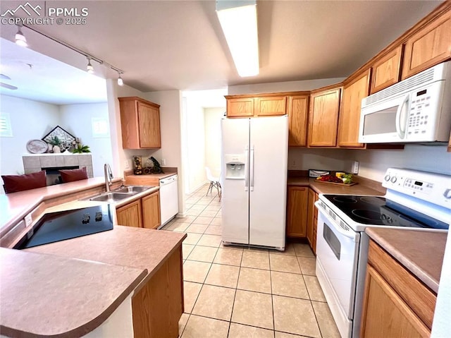 kitchen featuring sink, light tile patterned floors, track lighting, a tile fireplace, and white appliances