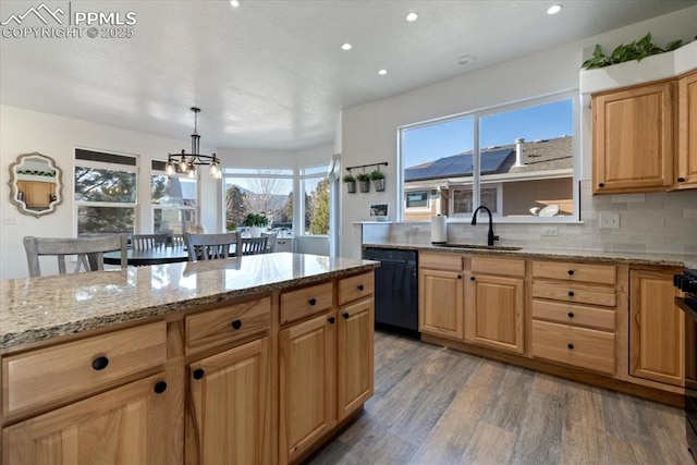 kitchen featuring pendant lighting, dishwasher, sink, light hardwood / wood-style floors, and light stone countertops