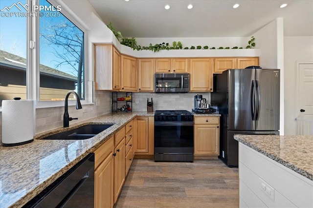 kitchen featuring sink, range with gas cooktop, light stone counters, refrigerator, and black dishwasher